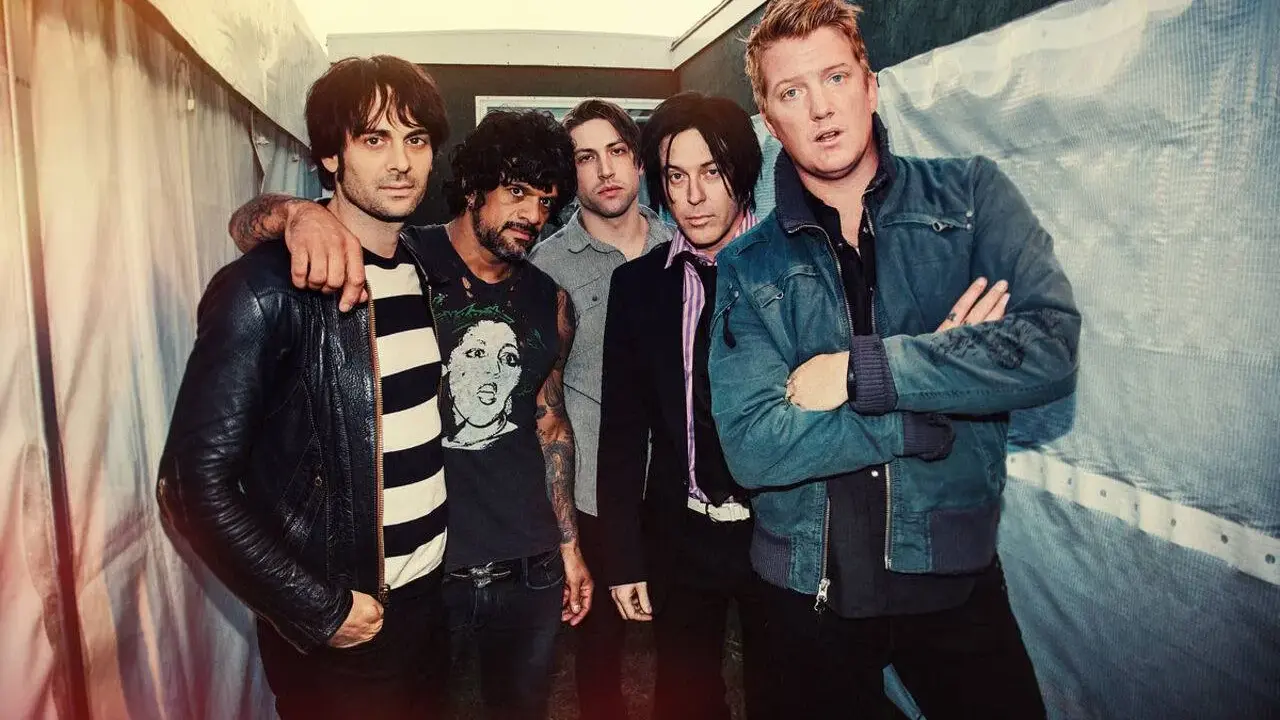 Les membres de Queens of the Stone Age posent ensemble, un groupe de rock emblématique.