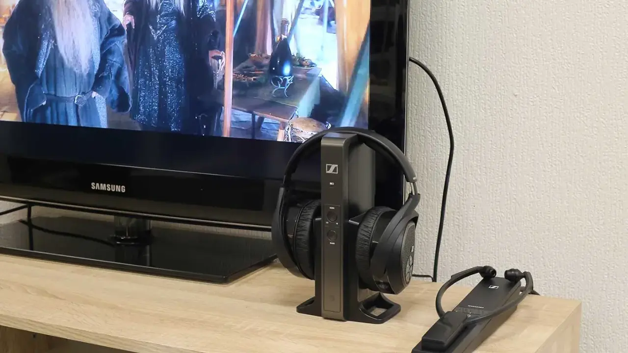 Un téléviseur Samsung diffuse un film, avec un casque sans fil sur son socle à côté. Idéal pour profiter du son tv et casque en même temps.