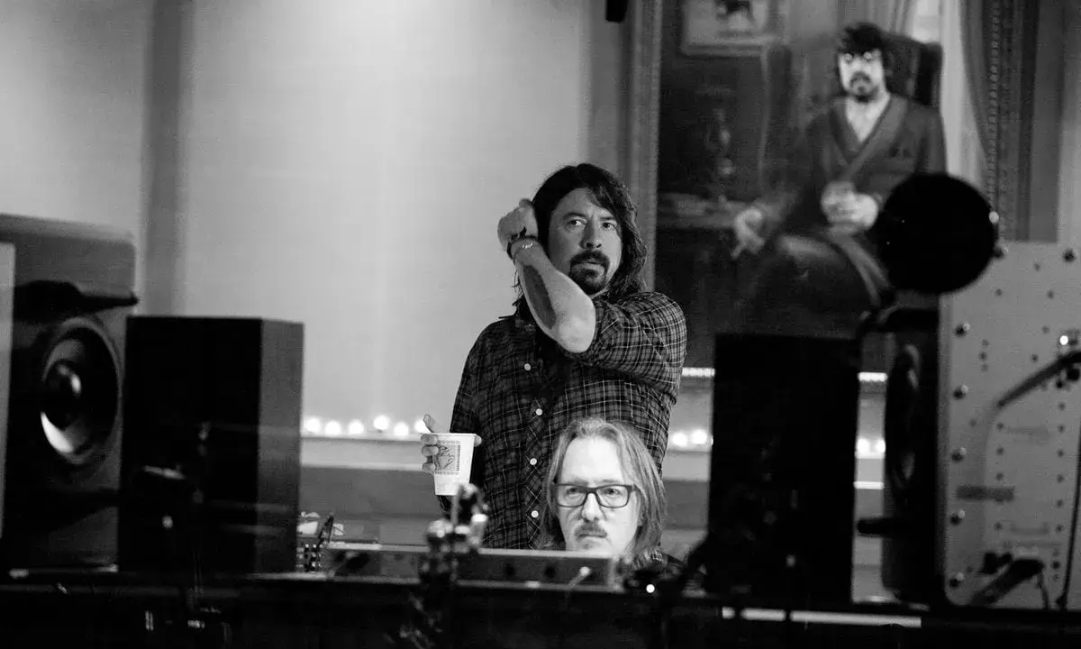 Dans ce studio d'enregistrement, deux hommes sont entourés d'équipements audio, créant une ambiance de **sound city**.