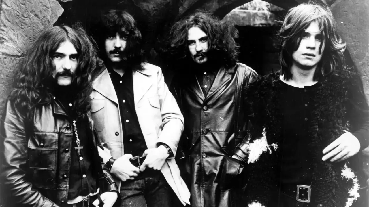 Les quatre membres de Black Sabbath posent devant une arche rocheuse, prêts à enregistrer leur premier album.