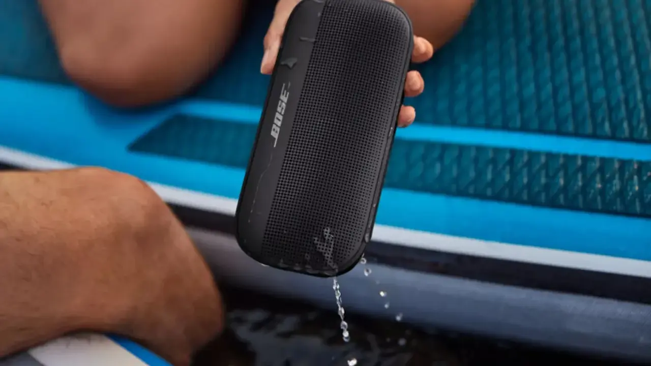 Enceinte Bose noire, étanche IPX4, éclaboussée par la pluie sur un paddleboard.