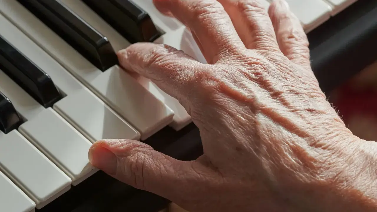 Main d'une personne âgée jouant du piano, un instrument facile à apprendre pour adulte.