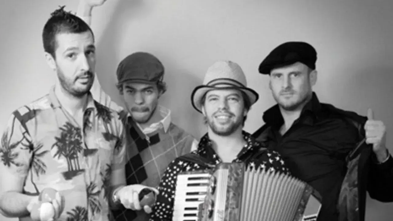 Le groupe java, avec son accordéoniste au centre, pose joyeusement. L'un des musiciens lève le poing, l'autre fait un clin d'œil.
