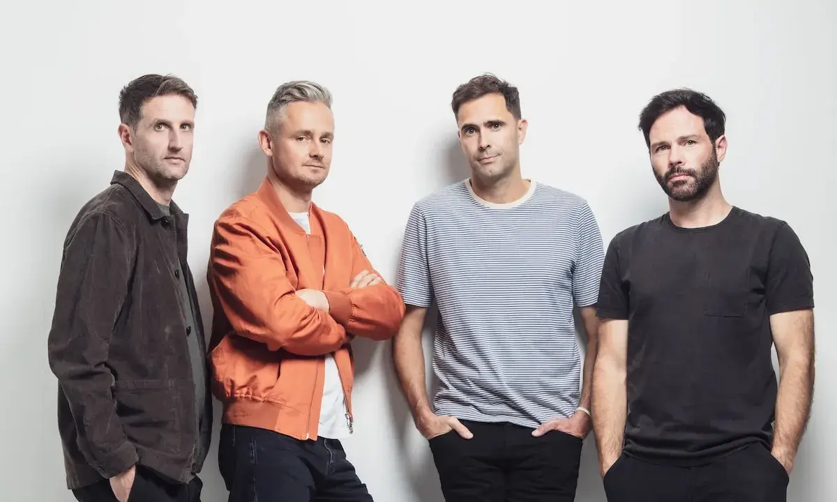 Le groupe Keane pose pour une photo, quatre hommes regardant la caméra.