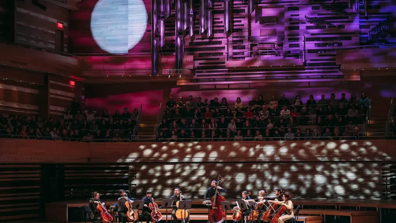 Un orchestre joue sur scène, éclairé par une lune projetée. C'est quoi un single ? Une pièce musicale unique, comme un solo d'un musicien.