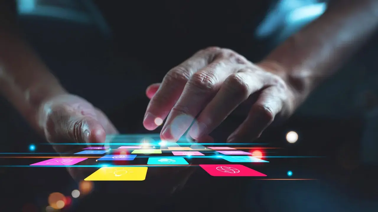 Main d'une personne naviguant sur une tablette avec des icônes colorées, suggérant une appli pour faire de la musique.