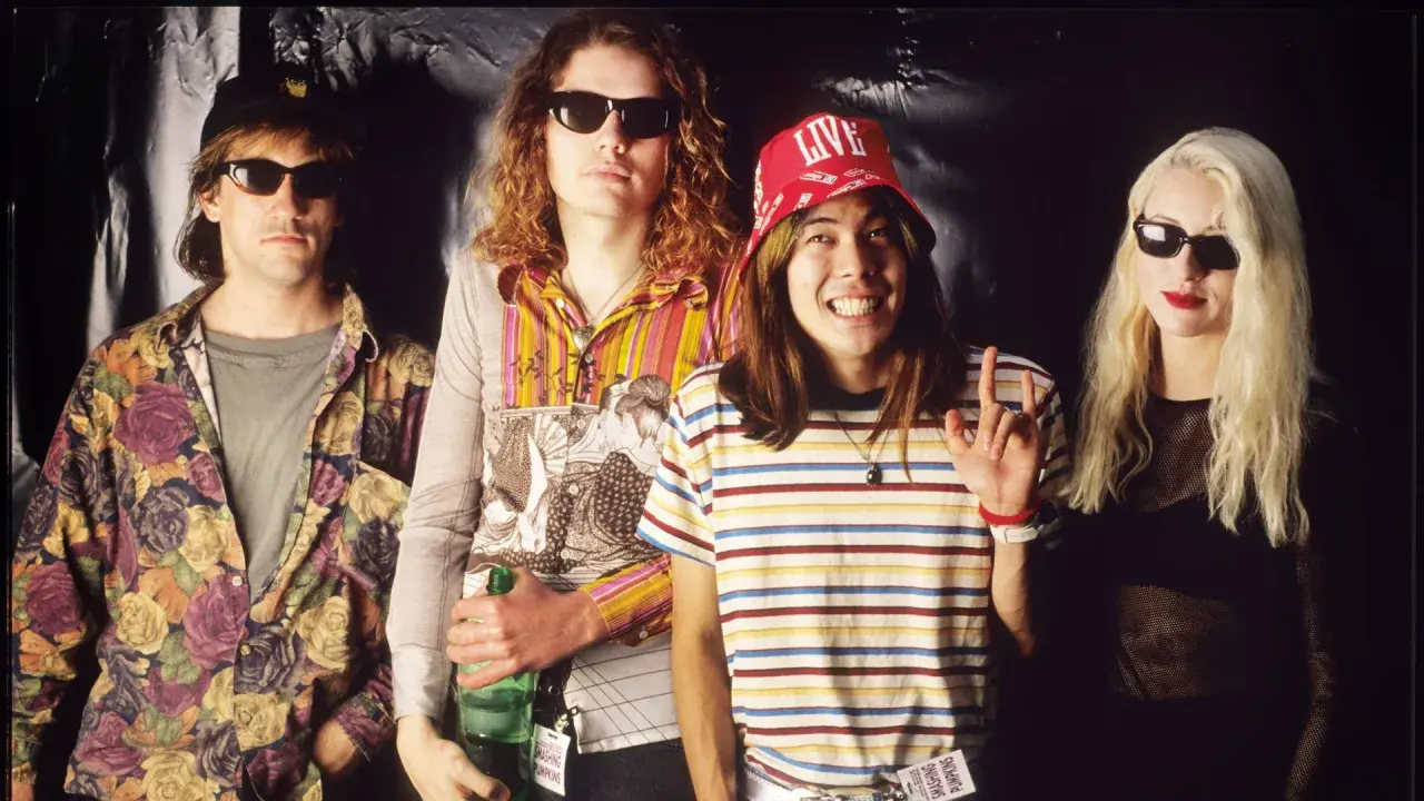 D'arcy Wretzky 2023, icône rock, pose avec les Smashing Pumpkins. Le groupe, dans un style années 90, arbore des tenues colorées et des lunettes de soleil.