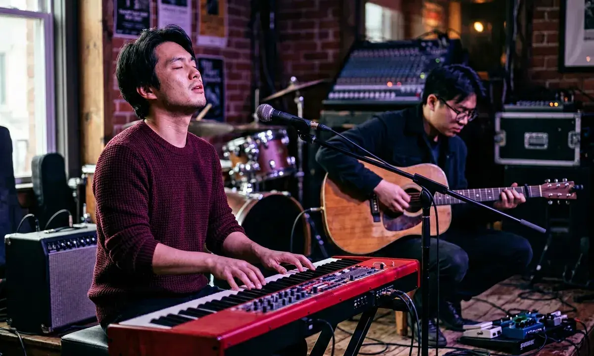 Deux musiciens jouent sur scène. L'un au piano rouge, l'autre à la guitare acoustique. Parfait pour un blog musique.