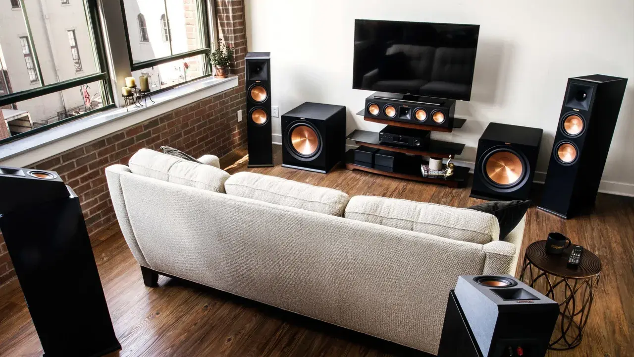 Salon moderne avec canapé clair, TV et système audio Klipsch pour une expérience sonore immersive, que ce soit en PCM ou Dolby Digital.