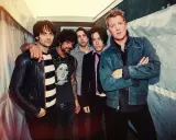 Les membres de Queens of the Stone Age posent ensemble, un groupe de rock emblématique.