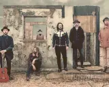 Cinq hommes posent devant une ruine. L'un tient une guitare. Une silhouette dans une fenêtre rappelle le corail, mer de miroirs.