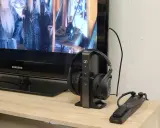 Un téléviseur Samsung diffuse un film, avec un casque sans fil sur son socle à côté. Idéal pour profiter du son tv et casque en même temps.