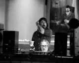 Dans ce studio d'enregistrement, deux hommes sont entourés d'équipements audio, créant une ambiance de **sound city**.