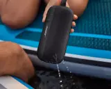 Enceinte Bose noire, étanche IPX4, éclaboussée par la pluie sur un paddleboard.