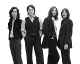 La composition des Beatles, quatre musiciens emblématiques posant ensemble sur fond blanc.
