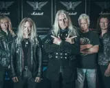 Le groupe Saxon, cinq musiciens aux cheveux longs, pose devant des amplis Marshall.