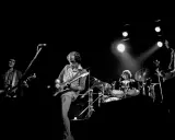 Quatre musiciens sur scène, guitares et batterie. Un aperçu de la **dire straits discography** en live.