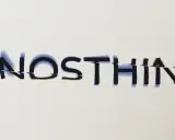 Le logo artiste musique "NOSTHIN" avec des lettres glitchées et une ombre bleutée sur fond blanc.