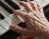 Main d'une personne âgée jouant du piano, un instrument facile à apprendre pour adulte.