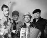 Le groupe java, avec son accordéoniste au centre, pose joyeusement. L'un des musiciens lève le poing, l'autre fait un clin d'œil.