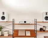 Élégant système audio blanc avec deux enceintes hifi et un lecteur CD sur des étagères en bois.