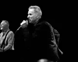Le chanteur, comme un Dr Feelgood, captive la foule avec sa voix puissante. Un guitariste l'accompagne sur scène.