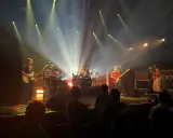 Une goat girl joue de la guitare sur scène, éclairée par des projecteurs.