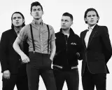 Les membres d'Arctic Monkeys posent pour une photo d'album. Le groupe est en noir et blanc, avec des styles variés.