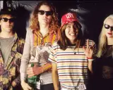 D'arcy Wretzky 2023, icône rock, pose avec les Smashing Pumpkins. Le groupe, dans un style années 90, arbore des tenues colorées et des lunettes de soleil.