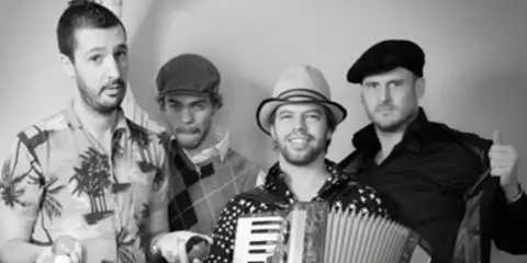 Le groupe java, avec son accordéoniste au centre, pose joyeusement. L'un des musiciens lève le poing, l'autre fait un clin d'œil.