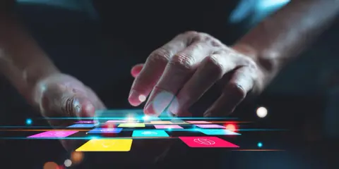Main d'une personne naviguant sur une tablette avec des icônes colorées, suggérant une appli pour faire de la musique.