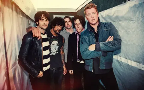 Les membres de Queens of the Stone Age posent ensemble, un groupe de rock emblématique.