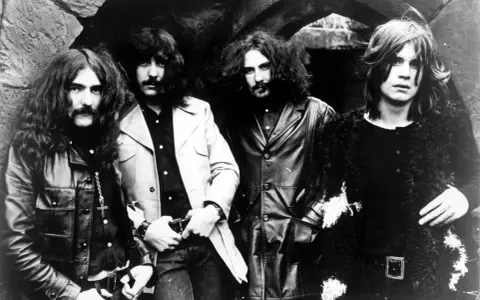 Les quatre membres de Black Sabbath posent devant une arche rocheuse, prêts à enregistrer leur premier album.