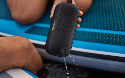 Enceinte Bose noire, étanche IPX4, éclaboussée par la pluie sur un paddleboard.
