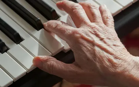 Main d'une personne âgée jouant du piano, un instrument facile à apprendre pour adulte.