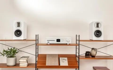 Élégant système audio blanc avec deux enceintes hifi et un lecteur CD sur des étagères en bois.