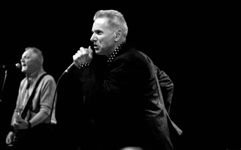 Le chanteur, comme un Dr Feelgood, captive la foule avec sa voix puissante. Un guitariste l'accompagne sur scène.