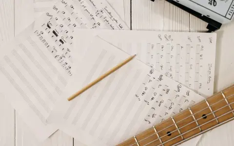 Feuilles de musique manuscrites, un crayon et une guitare. Le matériel parfait pour trouver l'inspiration pour écrire une chanson.
