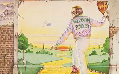 Elton John, sur la couverture du meilleur album Elton John, marche sur la route de briques jaunes vers un paysage idyllique.