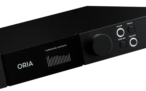 Un appareil audio noir ORIA avec un écran affichant des niveaux de sortie surround. Les commandes incluent un grand bouton rotatif et des boutons pour le volume, le profil, le down mix et la fonction, suggérant une expérience sonore immersive comme Dol...