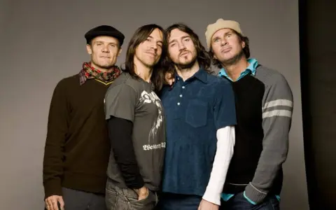 Les membres des Red Hot Chili Peppers posent ensemble, un groupe de rock légendaire.