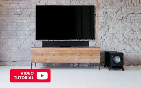 Un salon moderne avec une TV, une barre de son et un **pre out subwoofer** noir sur un meuble en bois.