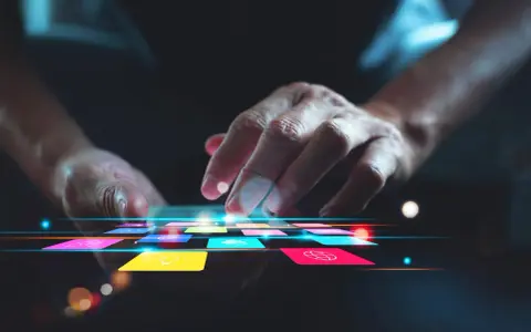 Main d'une personne naviguant sur une tablette avec des icônes colorées, suggérant une appli pour faire de la musique.