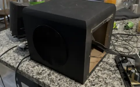Un caisson de basse noir ouvert sur une table. Pour savoir si un caisson de basse fonctionne, vérifiez les connexions et le circuit imprimé.