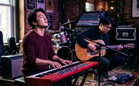 Deux musiciens jouent sur scène. L'un au piano rouge, l'autre à la guitare acoustique. Parfait pour un blog musique.
