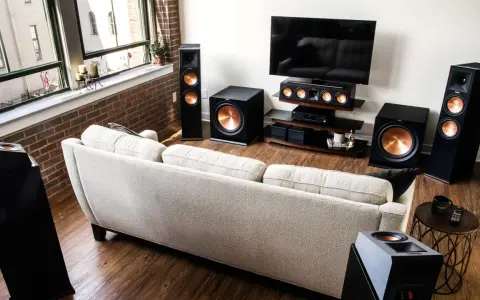 Salon moderne avec canapé clair, TV et système audio Klipsch pour une expérience sonore immersive, que ce soit en PCM ou Dolby Digital.