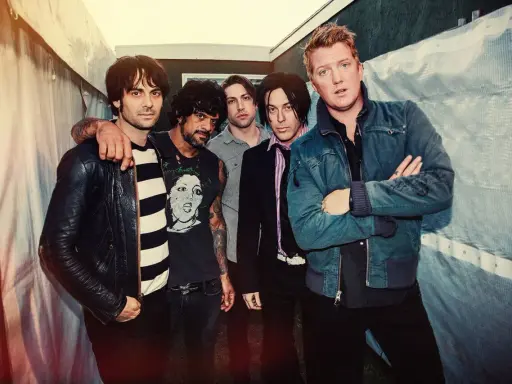 Les membres de Queens of the Stone Age posent ensemble, un groupe de rock emblématique.