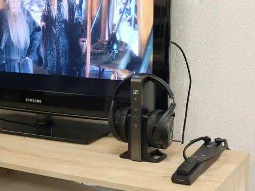 Un téléviseur Samsung diffuse un film, avec un casque sans fil sur son socle à côté. Idéal pour profiter du son tv et casque en même temps.