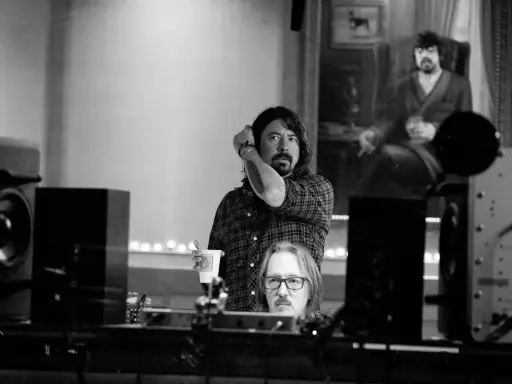 Dans ce studio d'enregistrement, deux hommes sont entourés d'équipements audio, créant une ambiance de **sound city**.