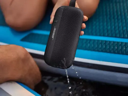 Enceinte Bose noire, étanche IPX4, éclaboussée par la pluie sur un paddleboard.